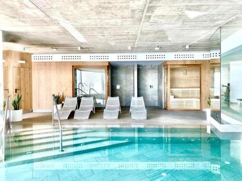 a lobby with a pool with chairs in it at Best Stupa Hills JM, magnífico apartamento y vistas in Benalmádena