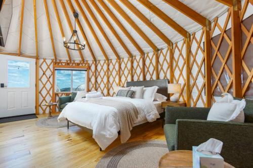 a bedroom with a bed and two chairs in a tent at Horizon Hideout - Modern Yurt in Brookville
