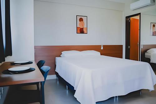 a bedroom with a bed and a table and a desk at Loft completo e climatizado a 2 minutos do centro in Cuiabá