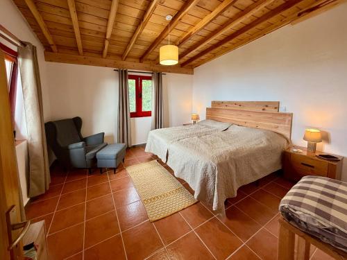 une chambre avec un lit et une chaise dans l'établissement Casa Cachalote - Ferienhaus auf den Azoren, à São Caetano