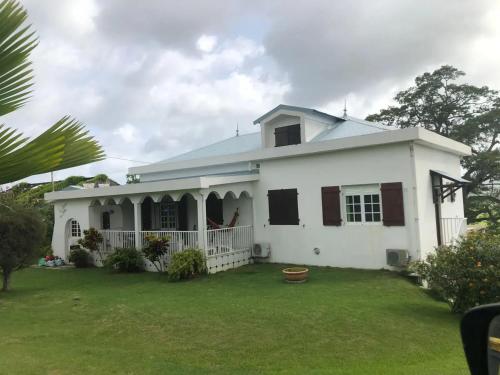 une maison blanche avec une cour verdoyante dans l'établissement Appartement spacieux à Rivière-Salée de 180 m², à Rivière-Salée