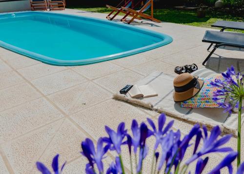 una piscina con un cappello, una sedia e fiori viola di Botanico a Villa Elisa