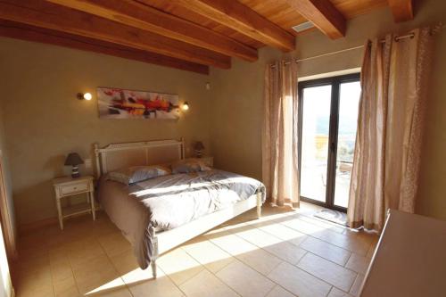 ein Schlafzimmer mit einem Bett und einem großen Fenster in der Unterkunft Charmante Villa en Pierre - Piscine in Vézac