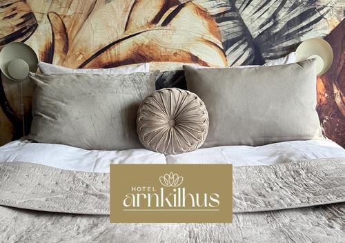 a bed with pillows and a sign that reads hotel amiability at Hotel Arnkilhus in Sønderborg