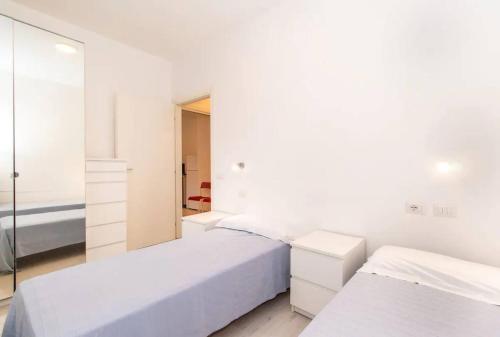 a white bedroom with two beds and a mirror at Villa tranquilla immersa nel verde a 2 Km dal mare in Chiavari