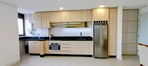a kitchen with wooden cabinets and a stainless steel refrigerator at Apartamento Novinho na Praia de Palmas em Gov Celso Ramos in Governador Celso Ramos