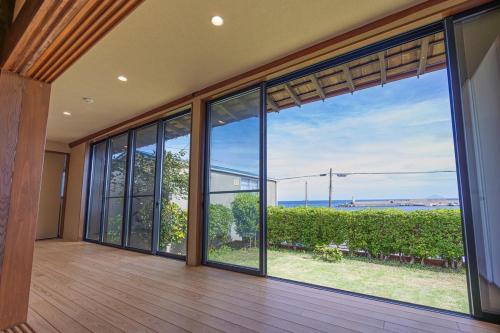 an empty house with large windows and a view of the ocean at 海が見える1棟貸し!バレルサウナ付きの家族で泊まれる貸し別荘!絶景とプライベート空間を満喫! in Higashiizu