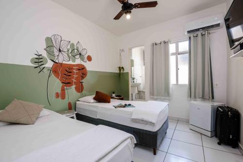 a bedroom with two beds and a painting on the wall at Hotel Prainha in Vila Velha