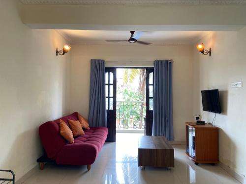 a living room with a red couch and a tv at Candolim Sea Breez in Candolim