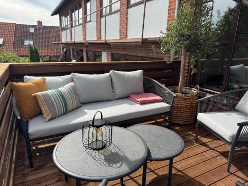 a patio with a couch and tables on a deck at Hotel Arnkilhus in Sønderborg
