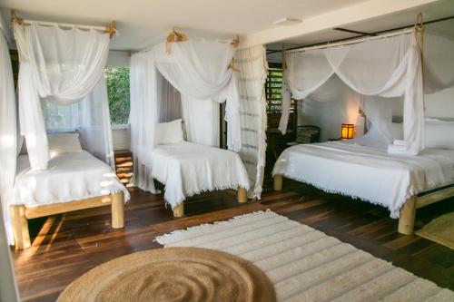 a bedroom with two beds and white curtains at Kitejuba Bungalows in Tatajuba