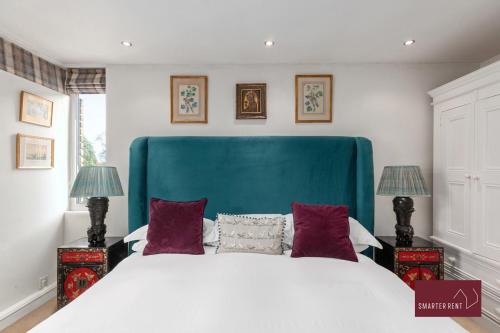 a bedroom with a large bed with a blue headboard at Richmond Three Bedroom Flat in Whitton