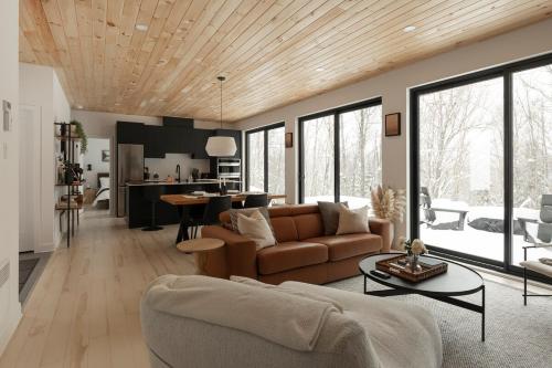 ein Wohnzimmer mit Couch und Tisch in der Unterkunft Forest Refuge - Fire - HotTub - Tremblant 15 min in La Conception