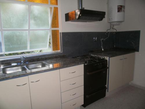 cocina con fogones negros y fregadero en Casa Cali, en Tanti Nuevo