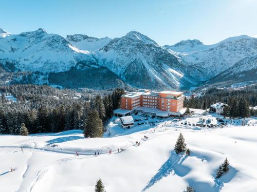 a hotel in the snow with mountains in the background at Hotel Prätschli in Arosa