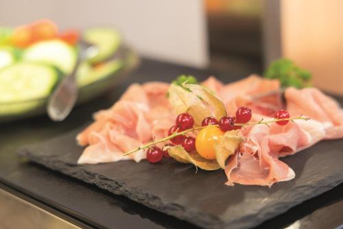 a plate of food with meat and fruit on it at Hotel Felix in Mietingen