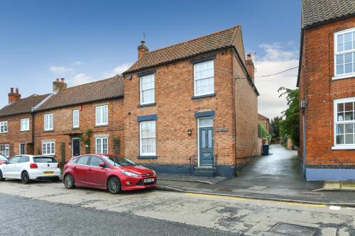 une voiture rouge garée devant un bâtiment en briques dans l'établissement Convenient 3-Bed Near Bingham Station & Town Centre, à Bingham