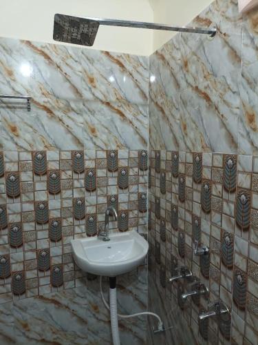 a bathroom with a sink and a marble wall at Anant Paying Guest house in Ayodhya