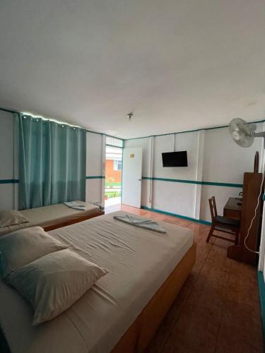 トゥリアルバにあるHotel Geliwaのベッドが2つと壁にテレビがある寝室