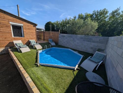 a small swimming pool in a yard with chairs and a fence at Gite Chez Tof et Ninie in Houlle