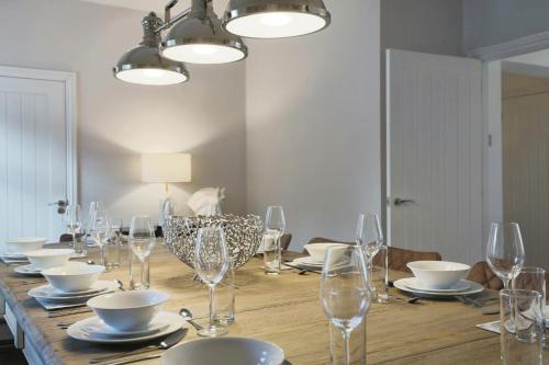 a long wooden table with glasses and plates on it at Luxurious 7-Bedroom Home in Solihull, close to NEC & BHX in Solihull