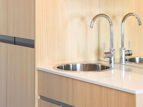a kitchen with a stainless steel sink and wooden cabinets at Mercure Brisbane Garden City in Brisbane