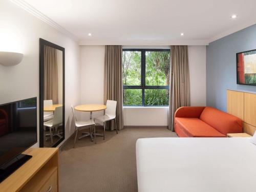 a hotel room with a bed and a table and a couch at Mercure Brisbane Garden City in Brisbane