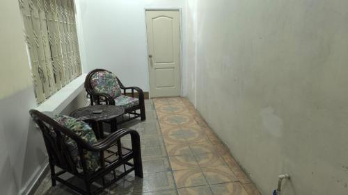 a hallway with two chairs and a table and a door at Nueva Acrópolis Sede SPS in San Pedro Sula