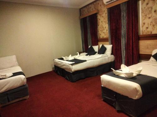 a hotel room with two beds and a red carpet at فندق لؤلؤة الجوار مكه in Makkah