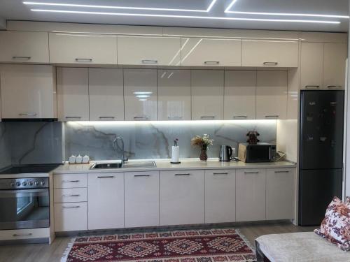 a kitchen with white cabinets and a black refrigerator at My Stay in Durres in Durrës