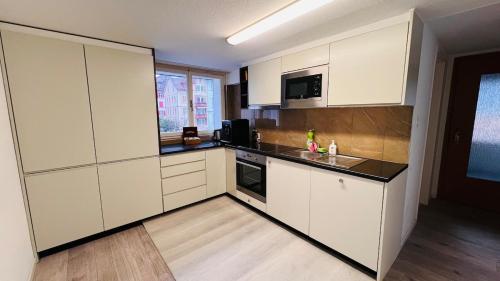 a kitchen with white cabinets and a black counter top at Cresta Apartment in St. Gallen
