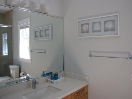 Baño blanco con lavabo y espejo en Riverfront Bed and Breakfast en North Vancouver