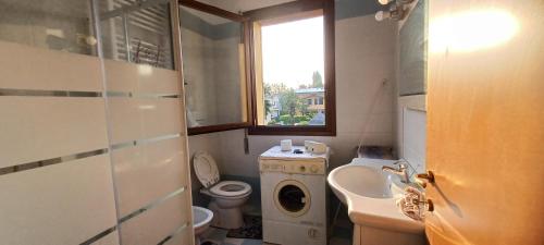 a bathroom with a toilet sink and a washing machine at Abate Appartament in Correzzola