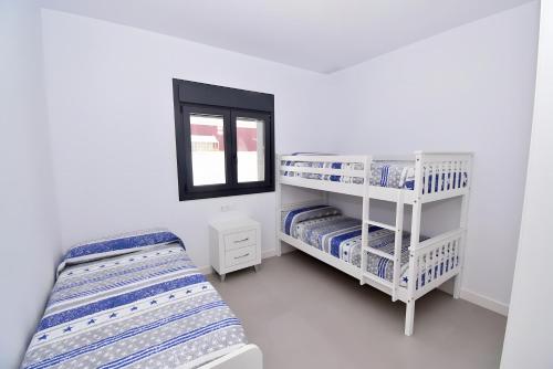 ein weißes Zimmer mit zwei Betten und einem Fenster in der Unterkunft Villa Private Oasis in Chiclana de la Frontera