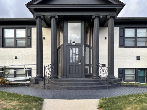 a house with a black door and columns at DTW Suites in Romulus