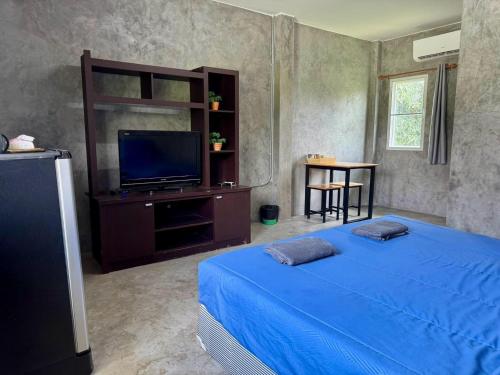 a bedroom with a blue bed and a flat screen tv at The Poom Garden Khao Yai in Ban Khanong Phra Klang (1)