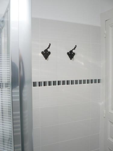 a white tiled bathroom with two black fixtures at La Maison de Saumur in Saumur