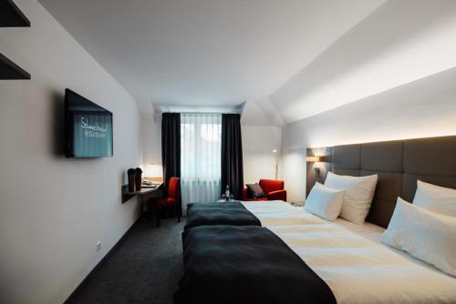 a hotel room with a large bed and a desk at Hotel Schmachtendorf in Oberhausen