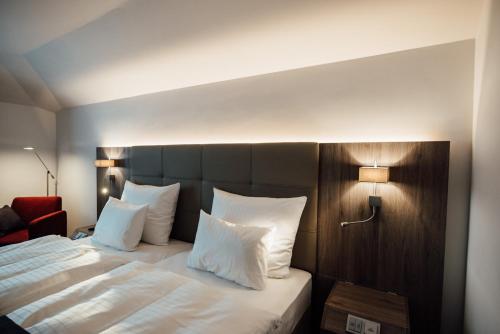 a bedroom with a large bed with white sheets and pillows at Hotel Schmachtendorf in Oberhausen