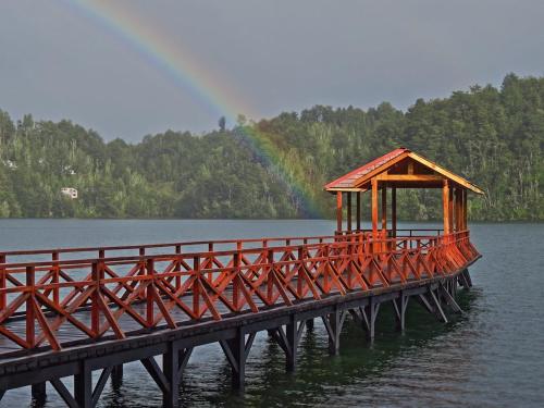 PiruquinaにあるLiwen Cabaña Pastahueの背景に虹がある水中の木製の橋
