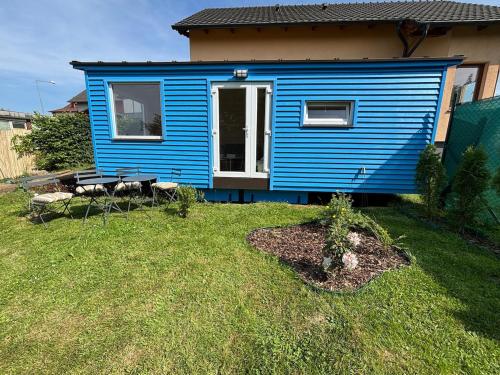 a blue tiny house in a yard at Celoročně obyvatelná maringotka Kratochvíle 
