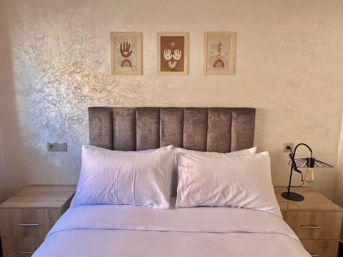 a bedroom with a bed with white sheets and three pictures on the wall at A12 Studio cosy Tamraght Idéal nomades & surfers in Tamraght Ouzdar