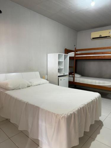 a bedroom with a large white bed and bunk beds at Pousada Sol Dourado in Jijoca de Jericoacoara