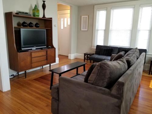 a living room with a couch and a flat screen tv at Bright Front Facing Unit - Private Front Farmers Porch in Manchester