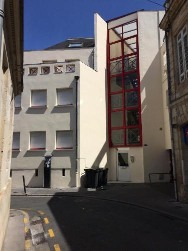 ボルドーにあるAppartement proche Victoireの赤窓のある白い建物