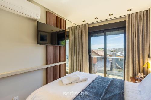 a bedroom with a bed and a large window at DLH - Apartamentos no Coração de Gramado Próximos à Rua Coberta in Gramado