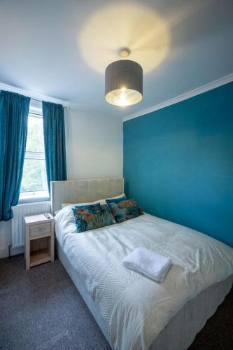 a bedroom with a bed with a blue wall at Rochdale Residence in Royal Tunbridge Wells