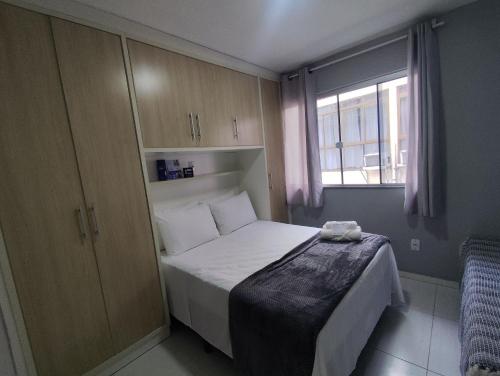 a small bedroom with a bed and a window at Aptos em prédio a 500m da Praia de Canasvieiras - GALs in Florianópolis