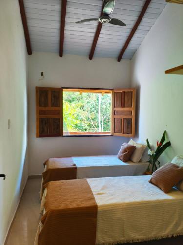 a bedroom with two beds and a window at Kitnets ESPELHO a 160 metros da Praia do Espelho in Praia do Espelho