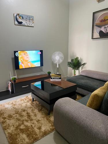 een woonkamer met een bank en een flatscreen-tv bij J&D Home NTINDA 02 in Kampala